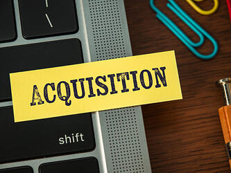 'Acquisition' written on sticky note on laptop'Acquisition' written on sticky note on laptop
